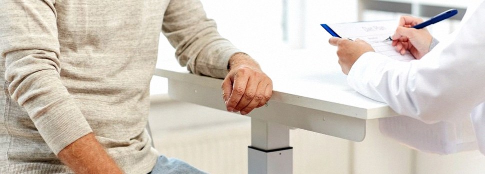 Man on doctor table talking to doctor with clipboard