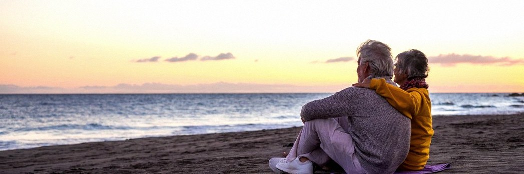 Older couple watching sunset on the beach