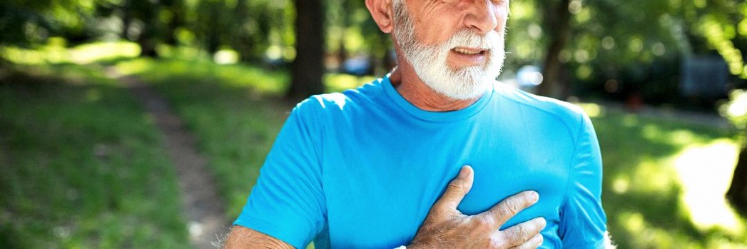 Man exercising outside gripping chest with one hand