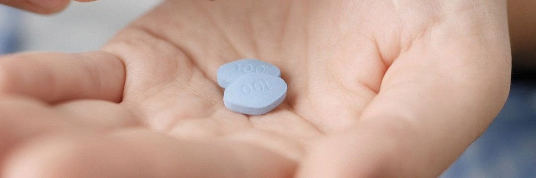 Man holding two blue pills 
