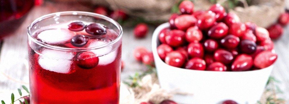 Glass of cranberry juice next to bowl of cranberries